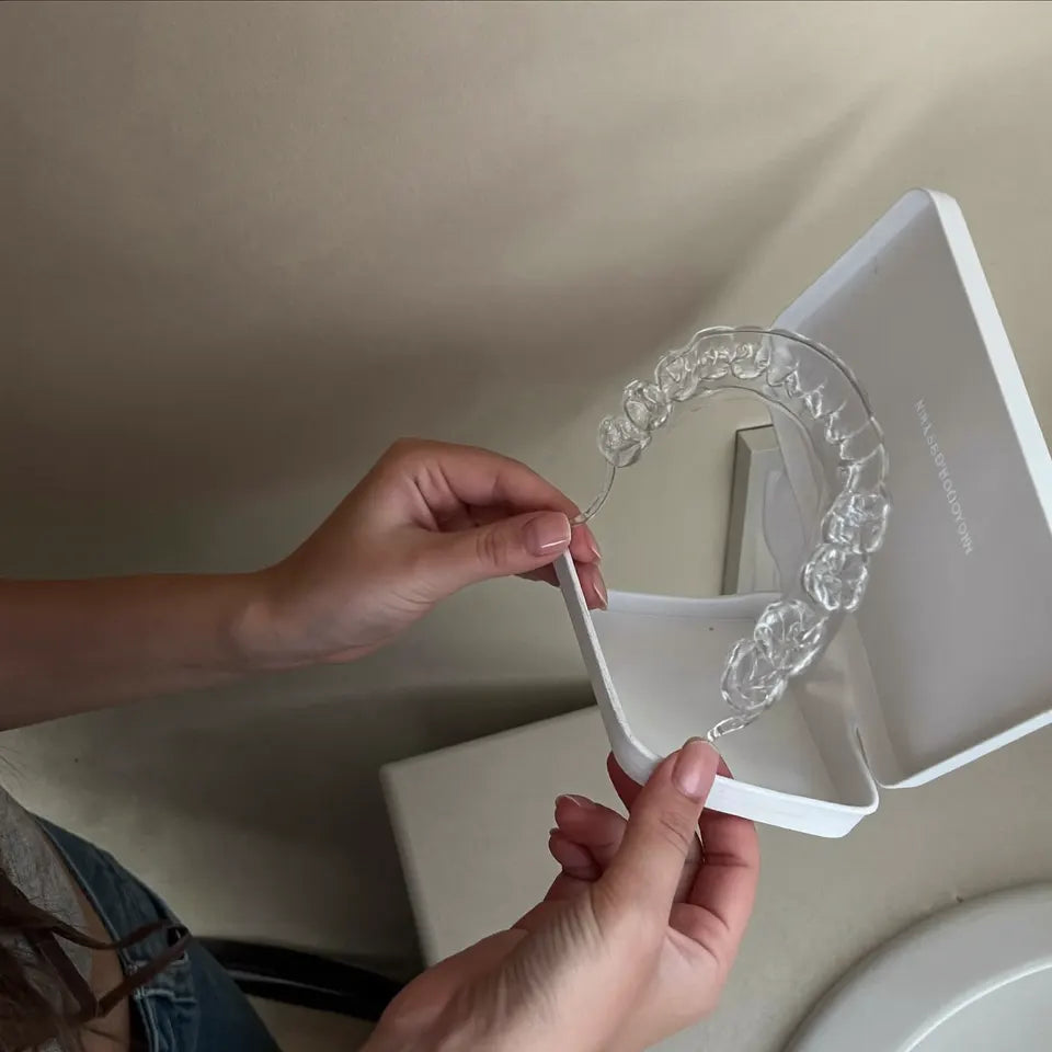 Hands putting a clear retainer into its case at the sink